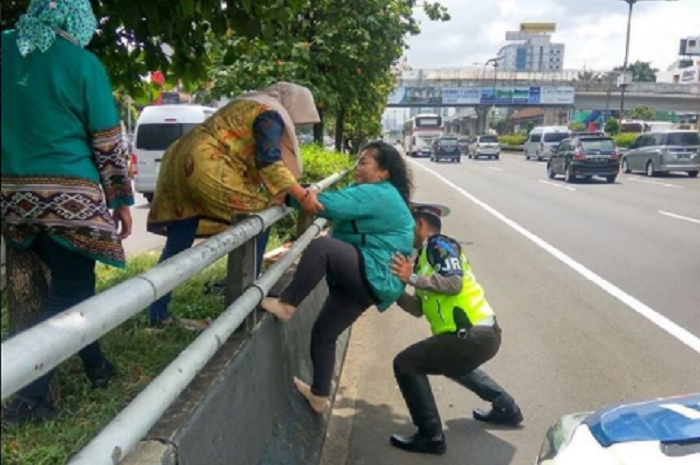 Seorang Petuga PJR membantu Ibu-ibu Memanjat Pembatas Jalan Tol