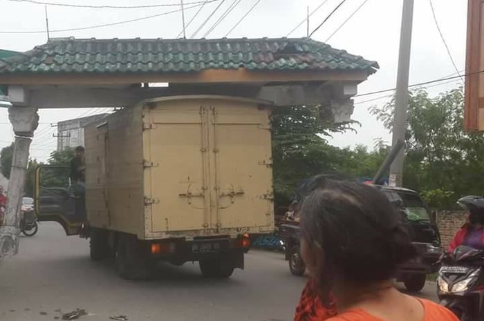 Sebuah truk boks berwarna kuning membawa atap gapura