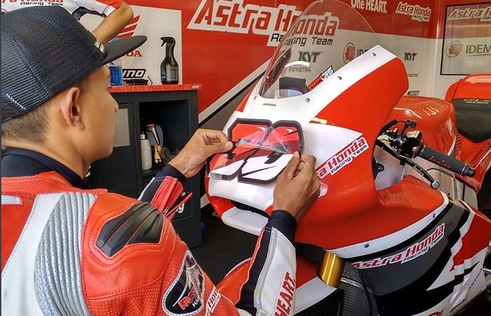 Dimas Ekky saat menempel nomor start baru di motornya