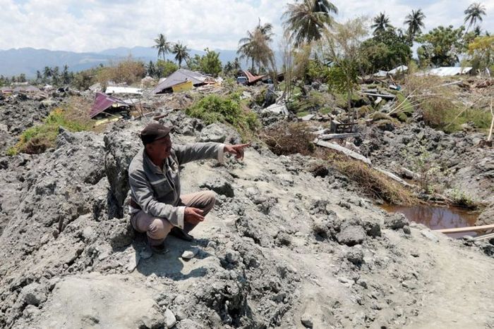 Seorang warga Palu menunjukkan sebuah rumah beton yang digulung lumpur yang keluar dari perut bumi dan berpindah ratusan meter di Kelurahan Petobo, Kecamatan Palu Selatan, Kota Palu, Sulawesi Tengah, pasca-gempa bermagnitudo 7,4.(KOMPAS.com/ROSYID A AZHAR)