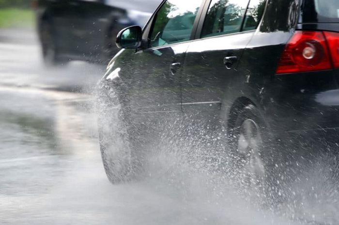 Ilustrasi mobil melaju di tengah hujan.  