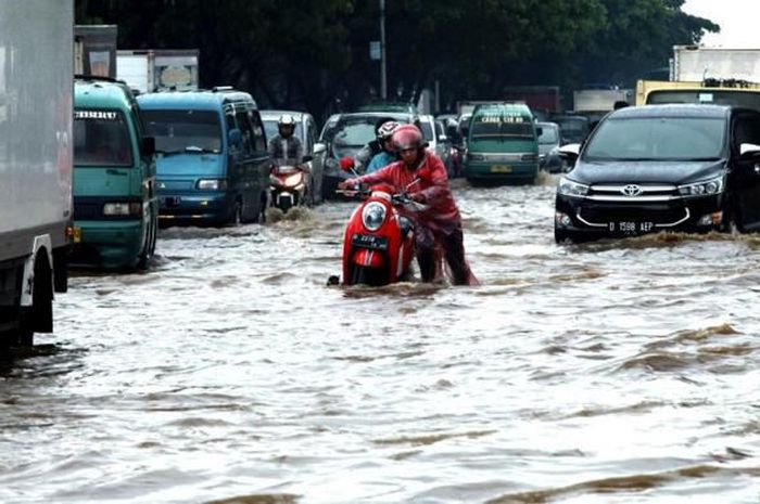 Pengendara motor yang melewati genangan