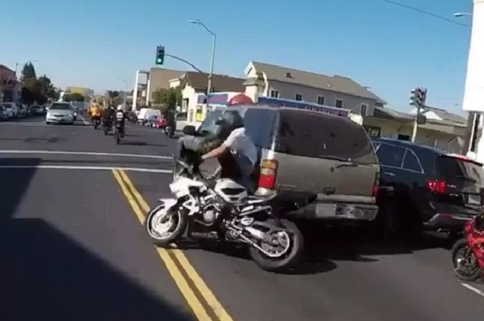 Biker yang melakukan wheelie di jalan raya