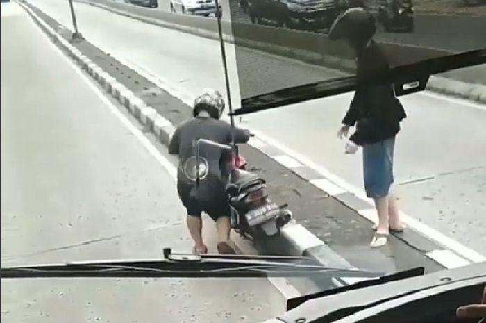 Pria yang mencoba menaiki motornya ke pembatas jalan