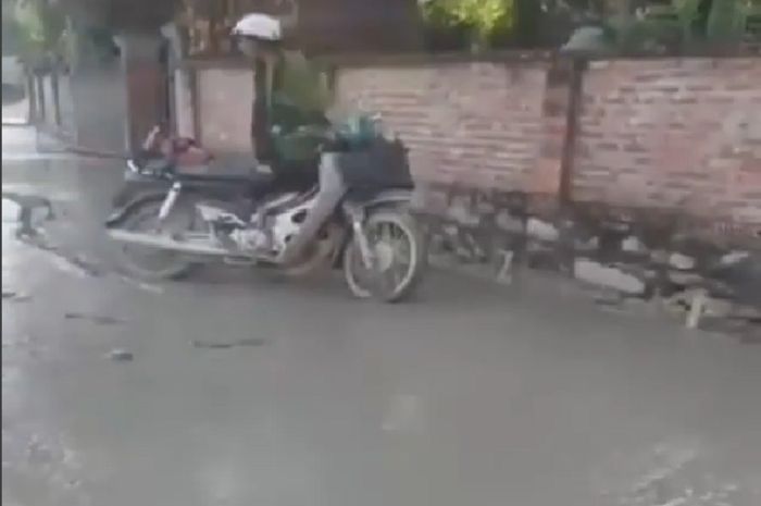 Pengendara yang melewati jalan yang belum selesai dicor