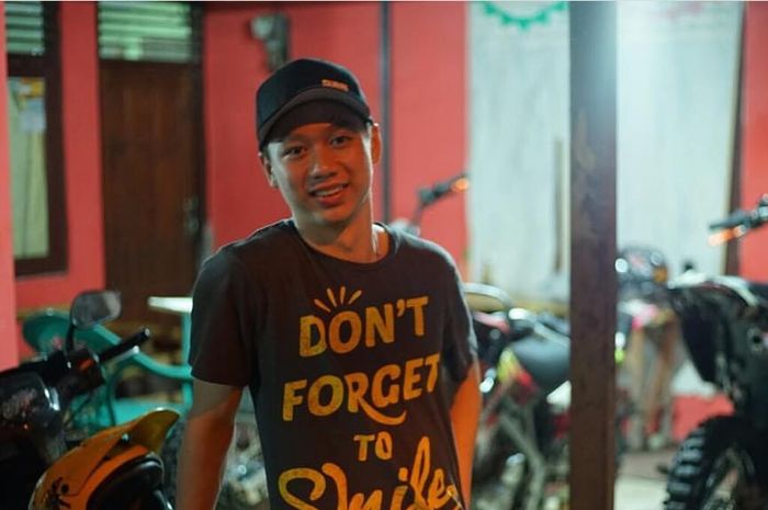 Kevin Sanjaya berpose di belakang motor trail.