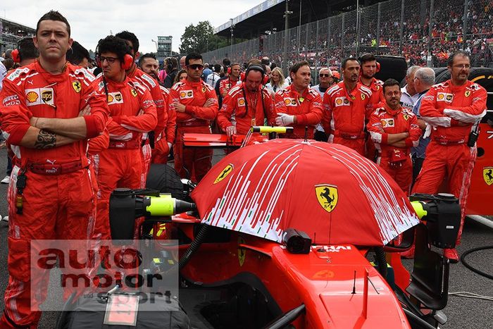 Kru Ferrari menutup kokpit mobil mereka dengan payung saat berada di grid start F1 Italia