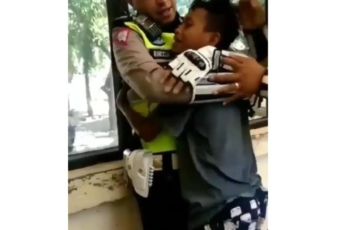 Seorang anak menangis dipelukan polisi karena takut ditilang