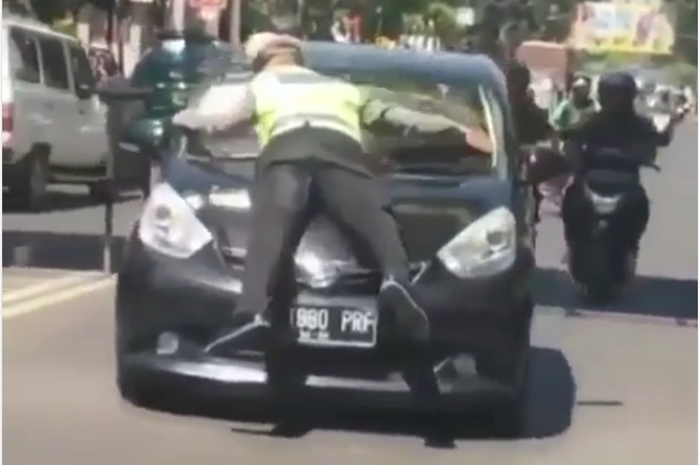 Polisi yang naik ke mobil Daihatsu Sirion yang tidak mau dihentikan