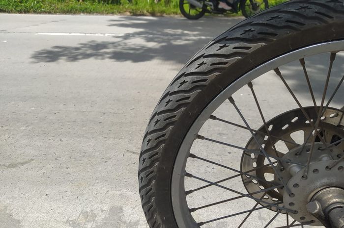 Ilustrasi ban motor melewati jalan beton.