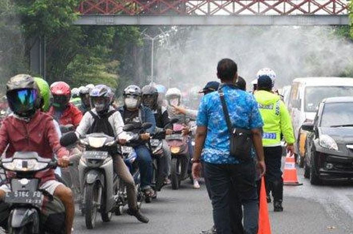 Petugas dari Dishub dan Polrestabes Surabaya melakukan penyemprotan disinfektan kepada kendaraan yang melintas di fronrage road Jalan Ahmad Yani yang merupakan salah satu pintu masuk ke Kota Surabaya, Jumat (27/3/2020)