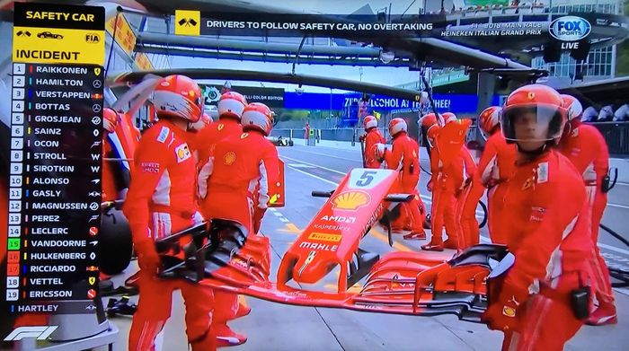 Kru tim Ferrari menanti Sebastian Vettel masuk pit untuk mengganti sayap depan mobil yang rusak setelah benturan pada  lap pembuka GP F1 Italia