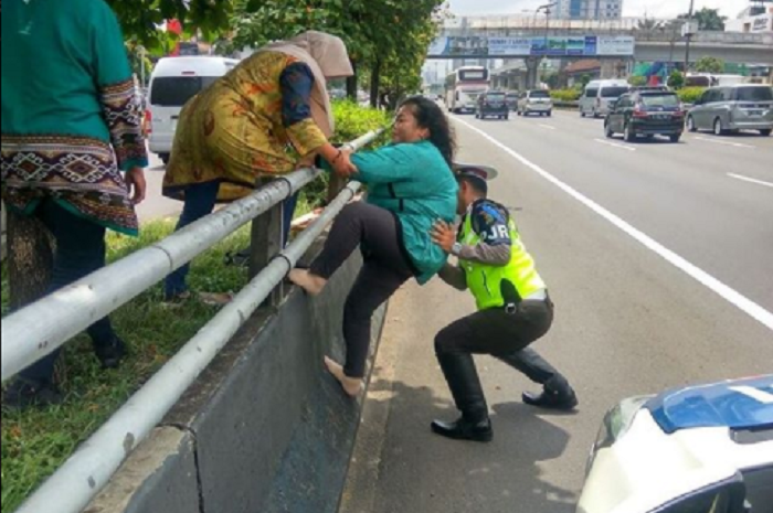 Seorang Petuga PJR membantu Ibu-ibu Memanjat Pembatas Jalan Tol