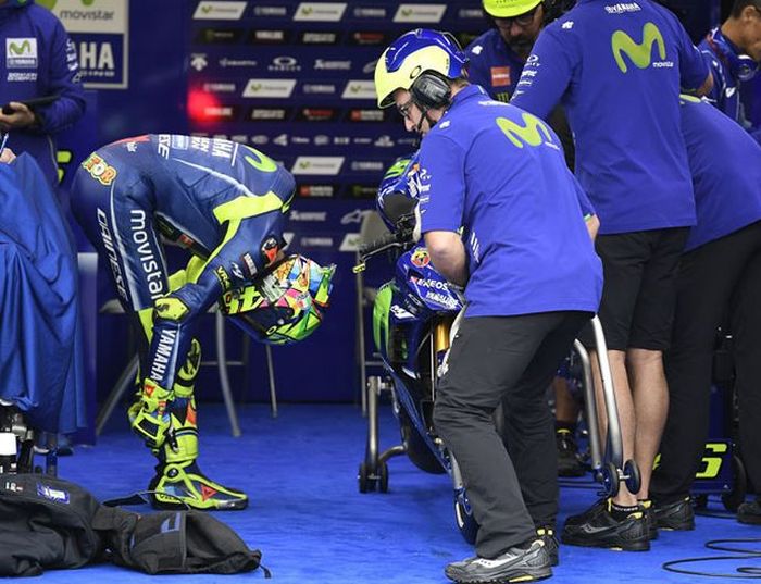 Valentino Rossi membungkuk di samping motornya