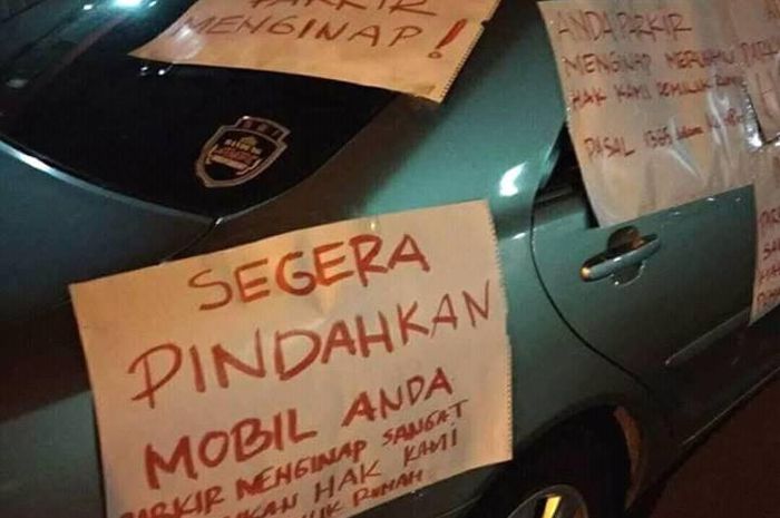 Sedan silver dengan tempelan 'poster demo' di bodinya gara-gara parkir sembarangan