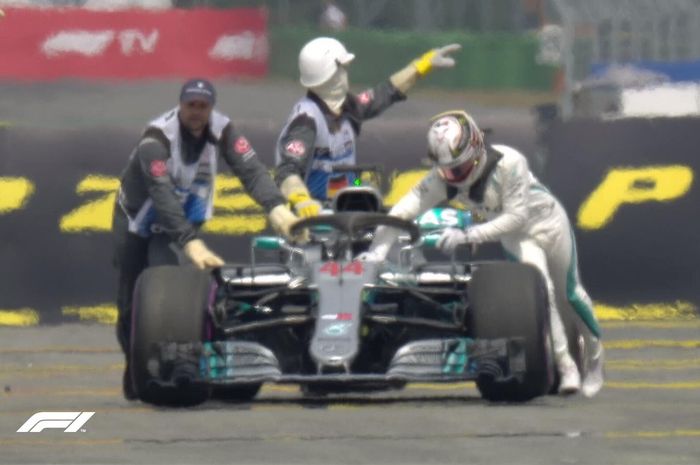 Lewis Hamilton coba mendorong mobilnya untuk kembali ke garasi pit tim Mercedes untuk diperbaiki, setelah berhenti pada kualifikasi GP F1 Jerman