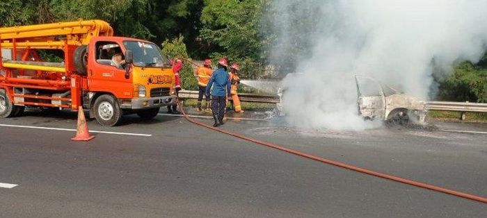 Petugas berusaha memadamkan api yang membakar Peugeot 806 di tol JORR, Cikunir, kota Bekasi