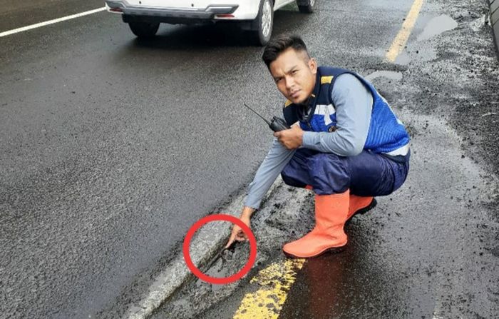 Petugas sedang memeriksa sambungan jalan tol yang tidak rata.