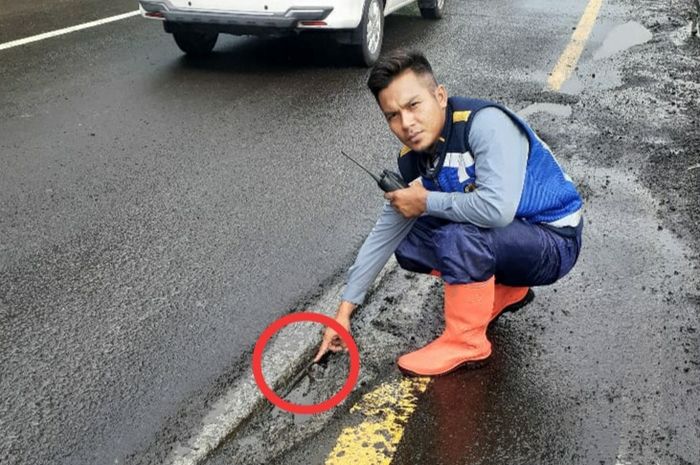 Petugas sedang memeriksa sambungan jalan tol yang tidak rata.