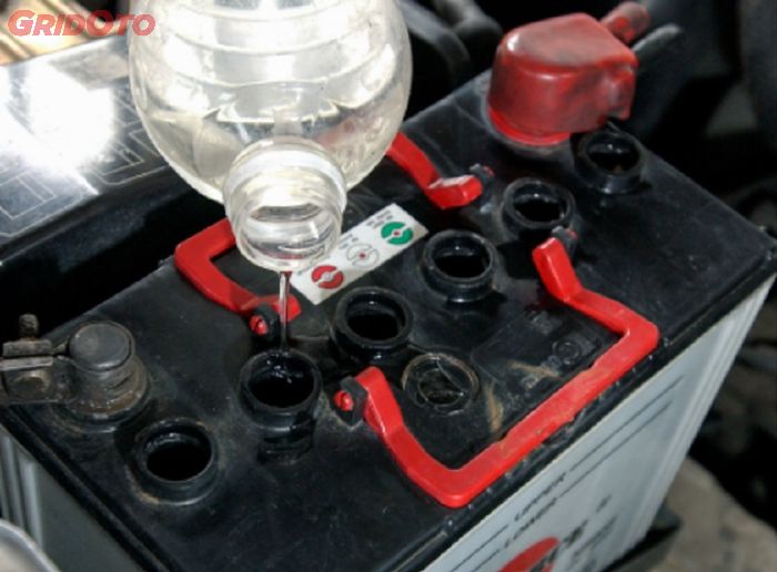 Ilustrasi menambahkan air aki kemasan botol biru