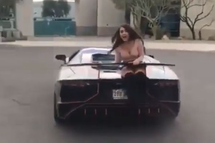 Cewek duduk di kap mesin Lamborghini dan diputar