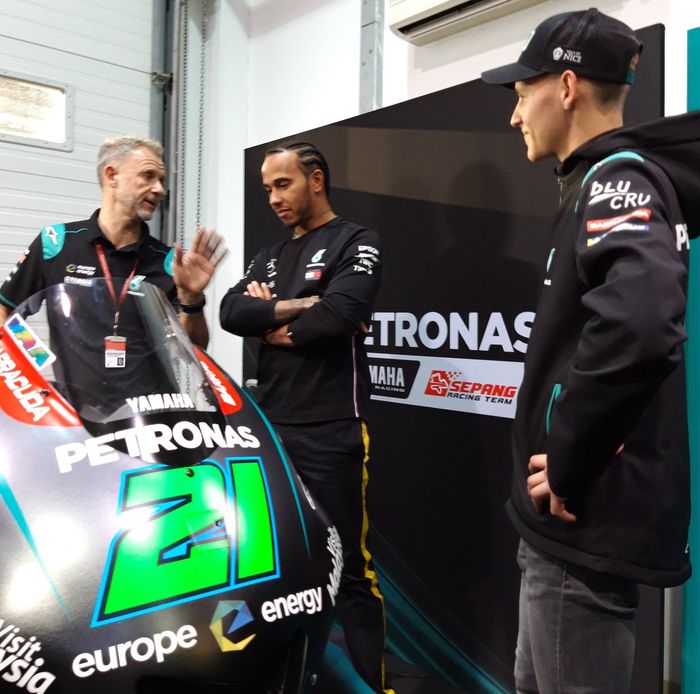 Lewis Hamilton mendengarkan informasi dari Wilco Zeelenberg, manajer tim Petronas Yamaha SRT, disaksikan Fabio Quartararo di MotoGP Qatar