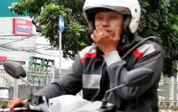 Ilustrasi pengendara motor merokok di jalan raya.