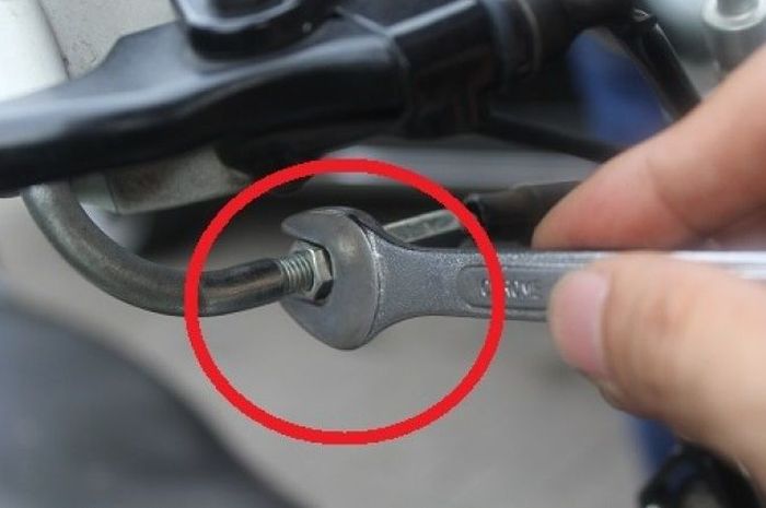 Posisi penyetel ketegangan tali gas ada di bawah selongsong gas.