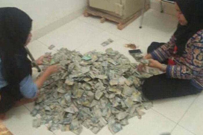 Dua karyawan yang menghitung uang pecahan Rp 2.000 untuk membeli Honda BeAT