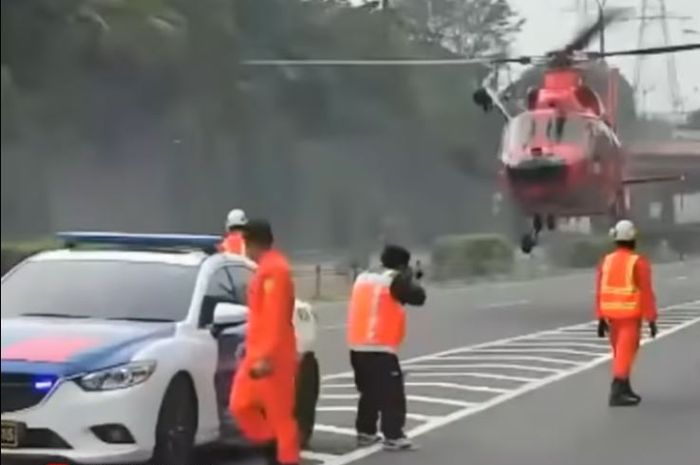 tangkap layar video yang memperlihatkan satu unit helikopter Basarnas mendarat di Tol Merak