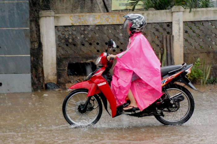Ilustrasi pengendara menggunakan jas hujan ponco