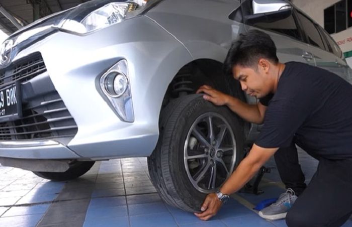 Mengecek kondisi bearing roda mobil bekas.