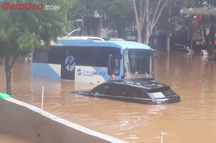 Range Rover yang diduga tipe Evoque mogok ditengah banjir bersama bus Transjakarta di Jalan Raya Kemang