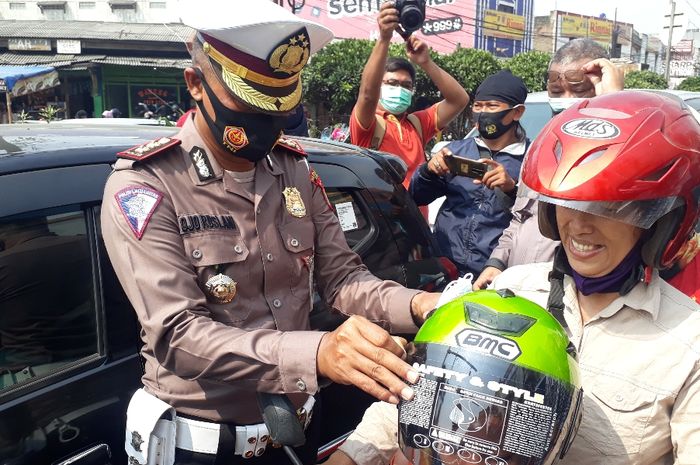 Kasatlantas Polres Metro Bekasi, AKBP Ojo Ruslani mebagikan helm gratis ke pada pengendara di Cikarang, Kabupaten Bekasi