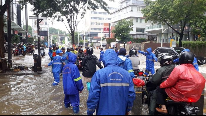 Sejumlah petugas Suku Dinas Sumber Daya Air membantu pemotor yang melewati banjir