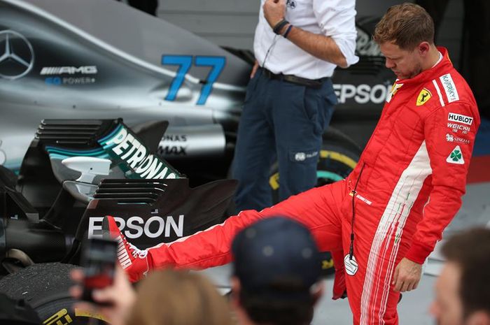 Sebastian Vettel memeriksa ban mobil Mercedes milik Lewis Hamilton usai balapan di GP F1 Rusia