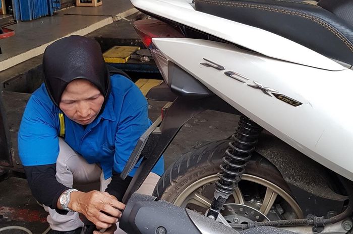 Mekanik bengkel sedang melakukan uji emisi motor