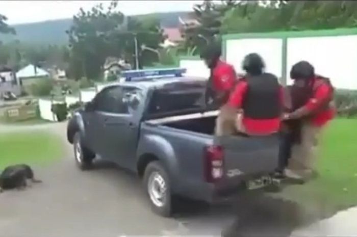 Anggota pasukan polisi menaiki mobil double cabin, kehilangan keseimbangan dan terjatuh
