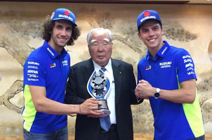 Alex Rins dan Joan Mir, berpose bersama ketua Suzuki Motor Corporation, Osamu Suzuki yang memegang trofi MotoGP Inggris
