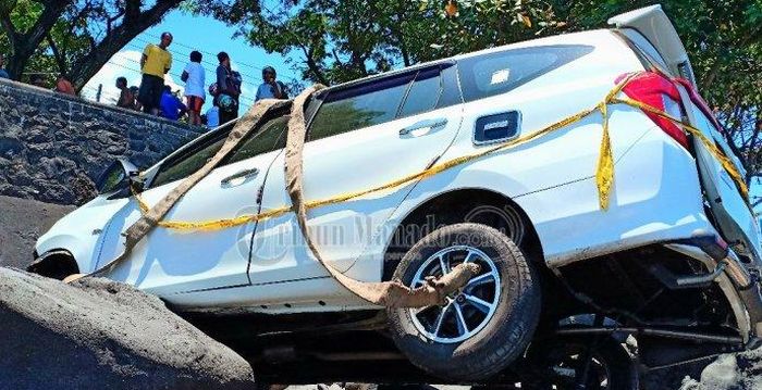 Toyota Calya sudah dipasangi tali dari crane untuk evakuasi dari dasar pantai Malalayang, Manado