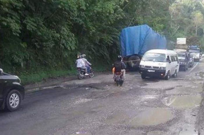 Para pengendara bermanuver menghindari lubang menganga di Jalan Lintas Sumatera tepatnya di Kecamatan Lumban Julu, Kabupaten Toba Samosir, Rabu (10/7/2019). 