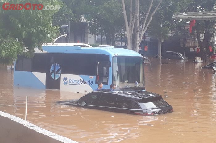 Range Rover yang diduga tipe Evoque mogok ditengah banjir bersama bus Transjakarta di Jalan Raya Kemang
