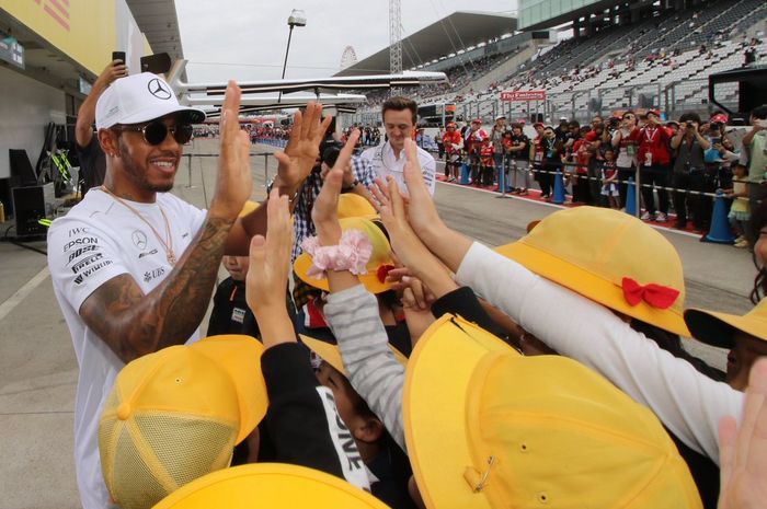 Pembalap tim Mercedes, Lewis Hamilton menebar senyum kepada para penggemar yang datang ke paddock timnya