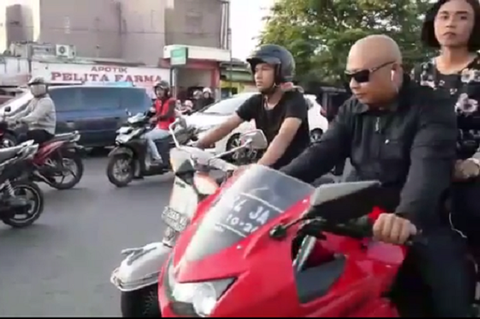 Pria mengendarai Kawasaki Ninja tak pakai helm, bergaya disebelah pengendara Vespa