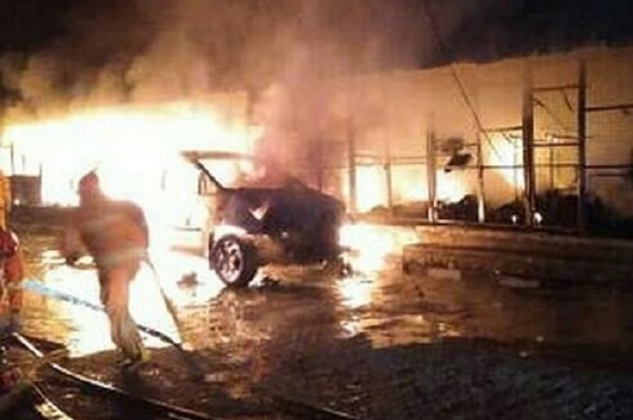 Petugas pemadam kebakaran berusaha memadamkan api yang melahap sebuah Toyota Innova
