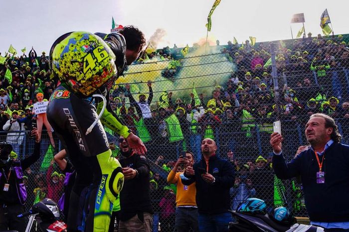 Valentino Rossi melemparkan sarung tangan dan helm khusus yang dibuat untuk tampil di Emilia Romagna ke arah tribun penonton