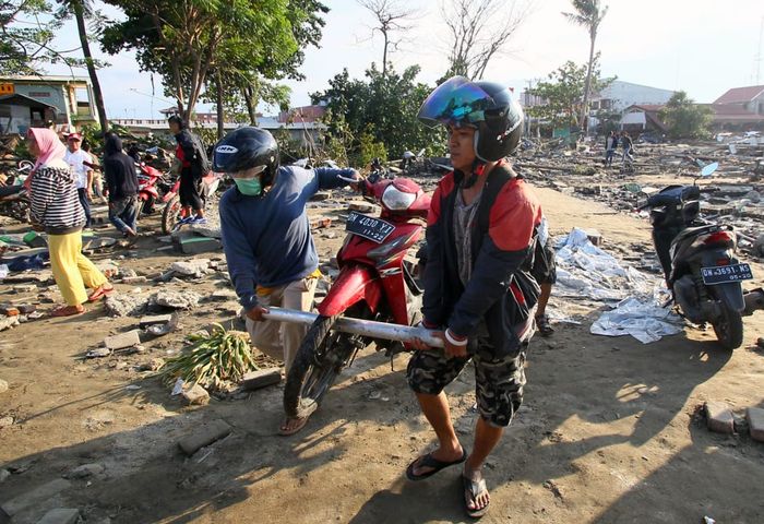 Sejumlah warga mengevakuasi motor pasca kejadian gempa dan tsunami di Donggala, Palu, Sulsel