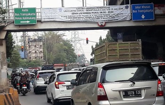 Spanduk kebijakan perluasan ganjil-genap yang terpasang di JPO Jalan DI Pandjaitan, Jakarta Timur.