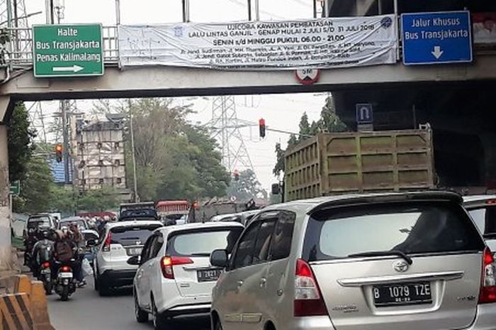 Spanduk kebijakan perluasan ganjil-genap yang terpasang di JPO Jalan DI Pandjaitan, Jakarta Timur. 