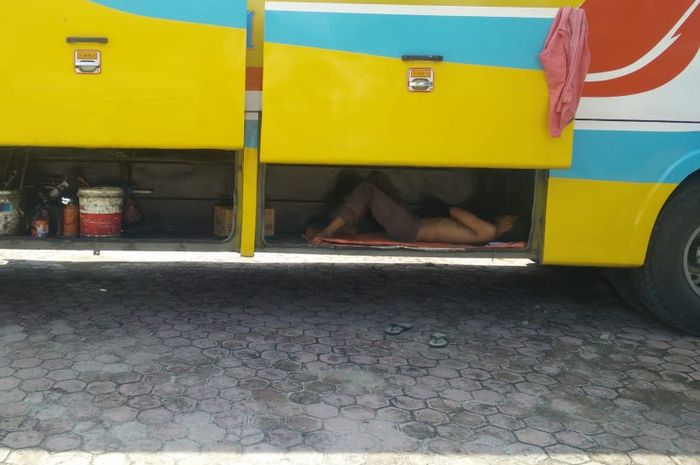 Seorang sopir  yang tengah tidur di dalam bagasi Bus